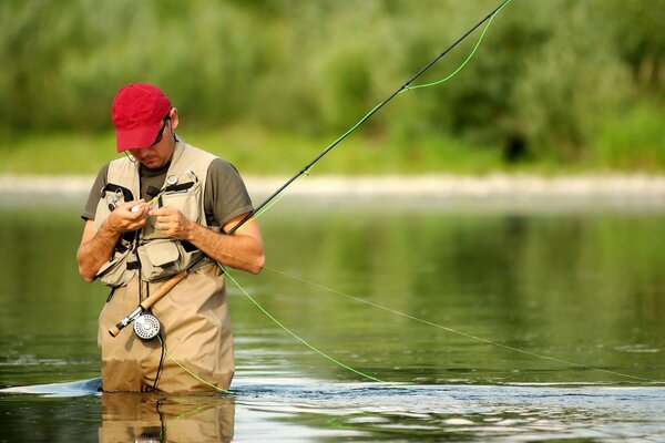 A fisherman in the river hooks tackle on a fishing rod