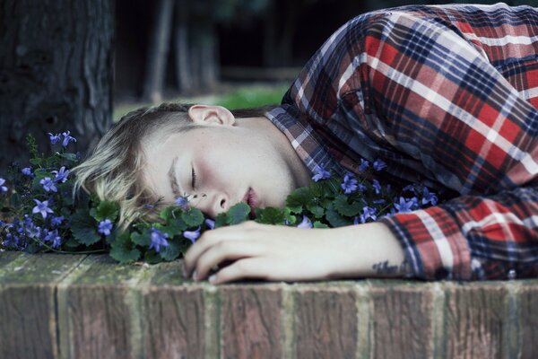 Un gars qui dort parmi les violettes sous un arbre