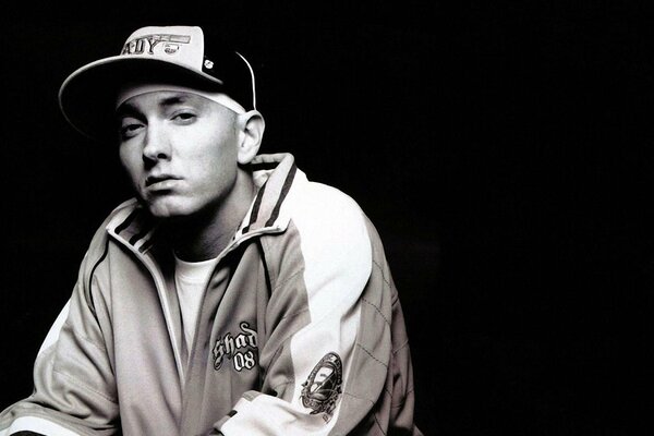 Eminem in a cap sits on a black background