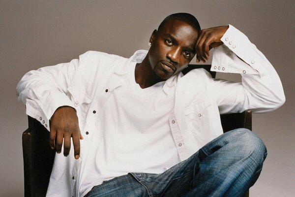 Cantante Akon in camicia bianca su una sedia