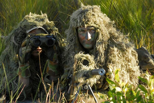 Two male snipers lie in ambush with a sniper rifle