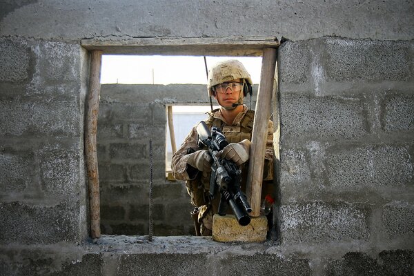 Foto eines Soldaten mit einer Waffe in der Hand auf einem Hintergrund von Ziegelwänden