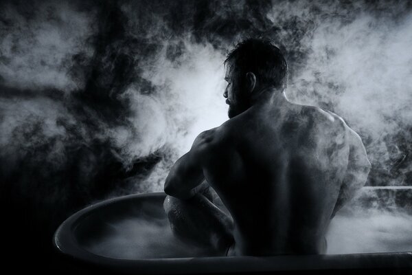 A muscular man is sitting in a hot tub