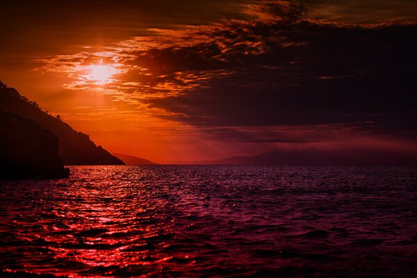 Schöner Sonnenuntergang am bergigen Meer