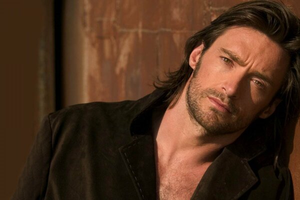 Hugh Jackman con i capelli lunghi in giacca sul corpo nudo