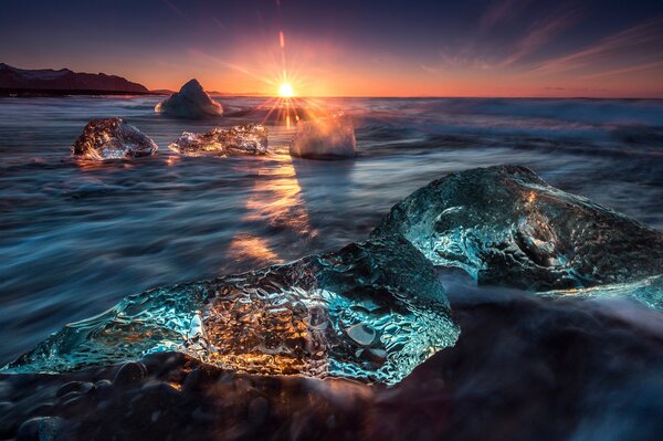 Sonnenuntergang über eisigen Felsen im Wasser