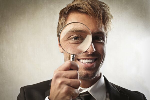 Smiling blonde looks through a magnifying glass