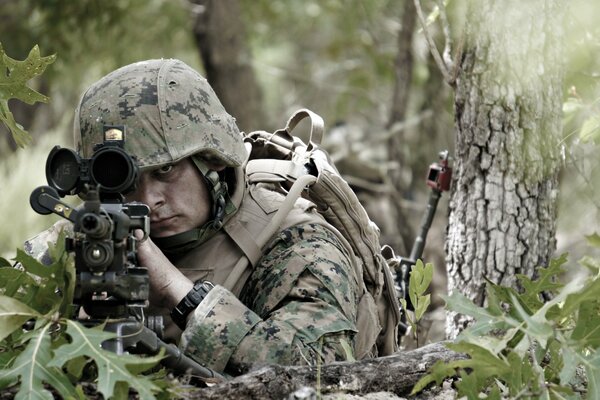 A soldier in a camouflage uniform looks through the scope