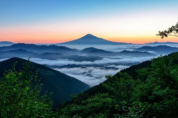 Fog descends from the mountains on the background of sunset