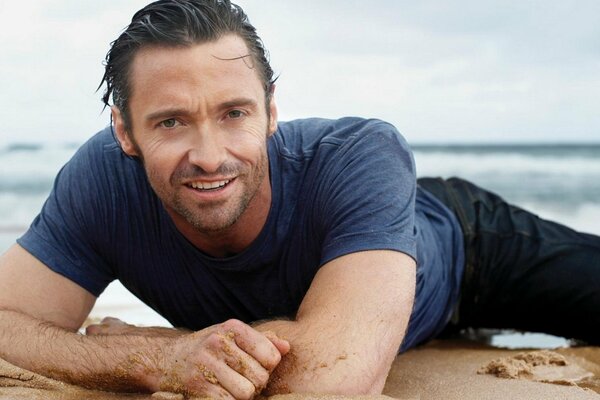 Hugh Jackman lies on the sand