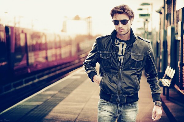 Mann mit Brille und Lederjacke am Bahnhof