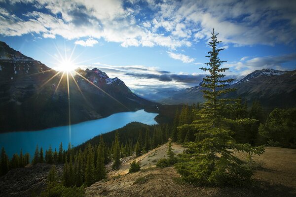 Sun over mountains and lake in a park in Alberta, Canada