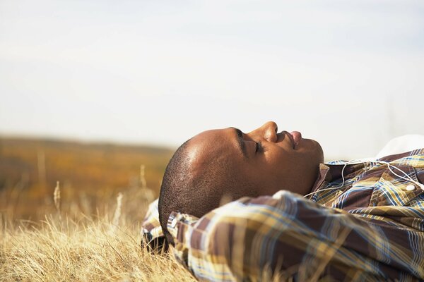 The guy is lying on the grass and dreaming