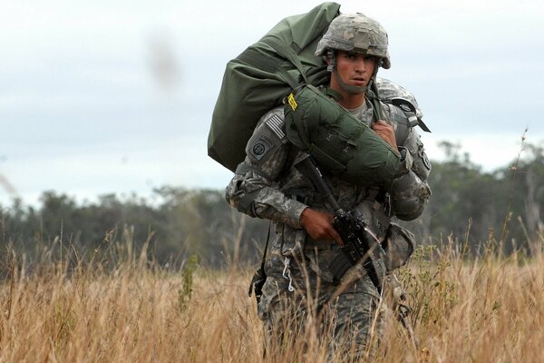 A soldier with a machine gun walks across the field