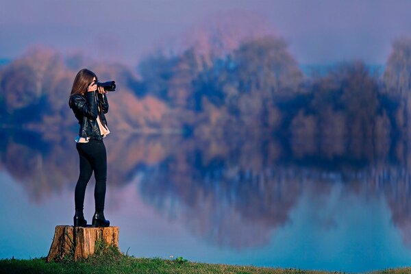 The brunette photographer shoots a beautiful lake landscape in autumn