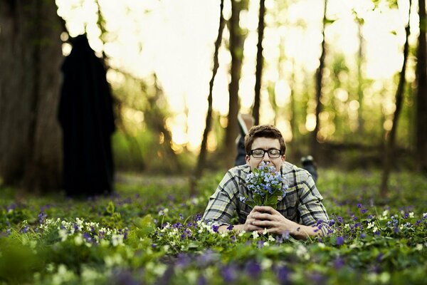 Guy se trouve sur l herbe avec un bouquet de fleurs