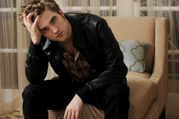 Robert Pattinson is sitting on a chair