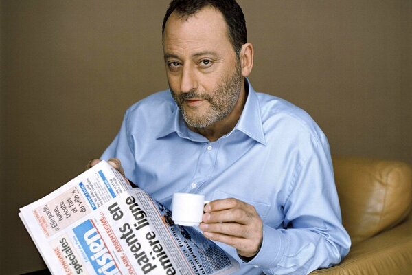 Jean Reno mit einer Zeitung und einer Tasse Kaffee