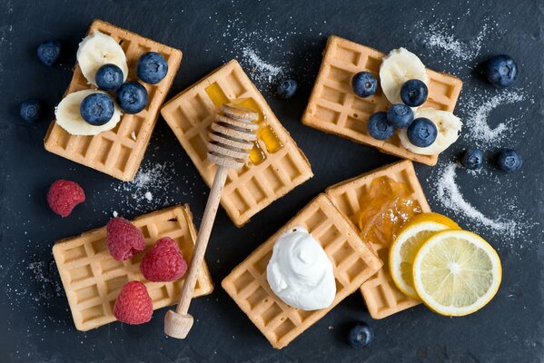 Waffeln mit Beeren, Früchten und Süßigkeiten verziert