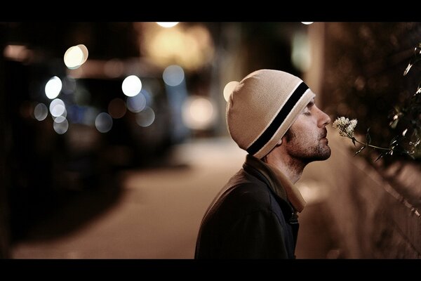 Homme dans la rue reniflant une fleur