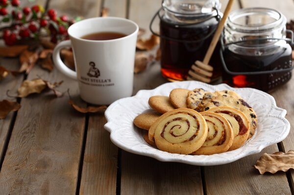 Té en una taza blanca con galletas y miel en una mesa de madera