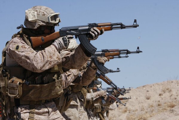 Soldiers in equipment shoot from a Kalashnikov