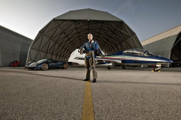 Pilot on the background of an airplane and a sports car