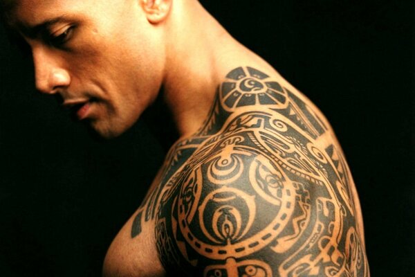 The actor nicknamed the rock shows his tattoo