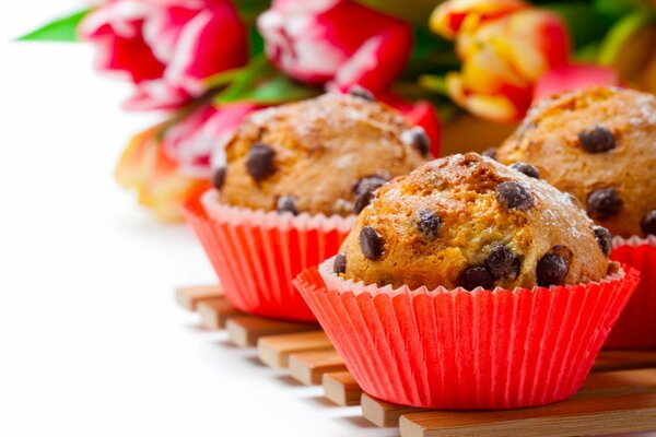 Cupcakes with chocolate on the background of a bouquet of flowers