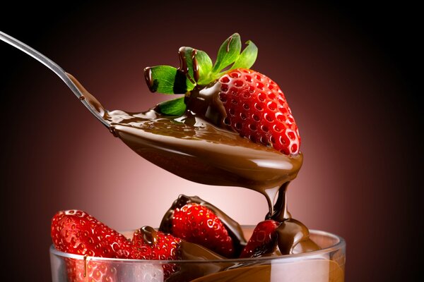 Fresas cubiertas de chocolate en un vaso con una cuchara