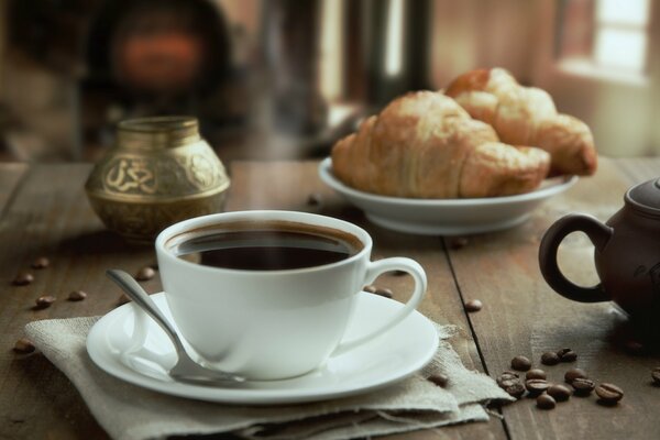 Natura morta. Tazza con piattino. Croissant su un piatto