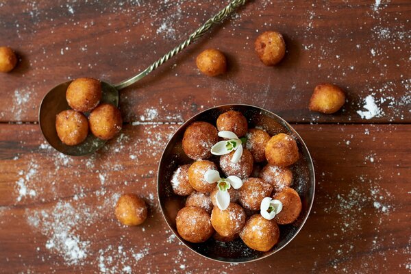 Donuts on a wooden table sprinkled with powdered sugar