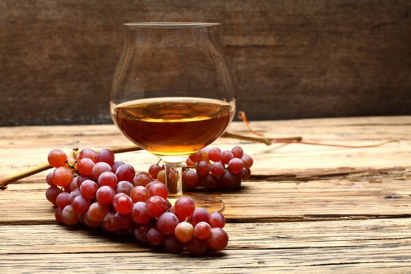 Un vaso de coñac y un racimo de uvas en la mesa