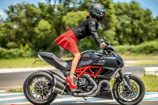 Fille en jupe, talons et casque sur une moto