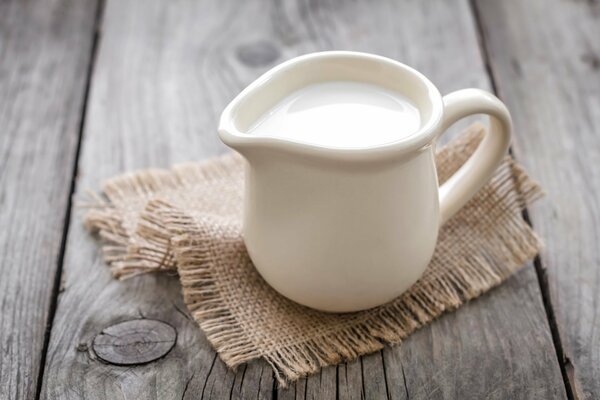 Lattiera bianca con latte su un tovagliolo