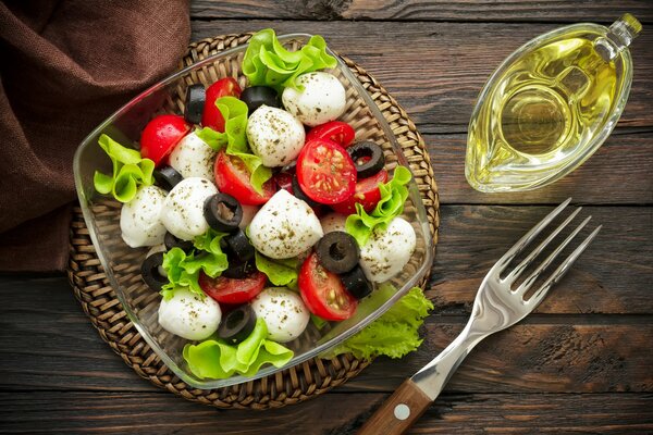 Bodegón con ensalada Caprese brillante, tenedor y aceite de oliva para aderezo