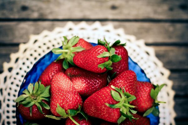 Fragole in una ciotola blu su un tovagliolo di pizzo