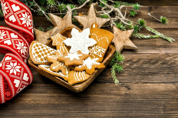 Weihnachtsgebäck mit Glasur. Tannenzweige und rotes Weihnachtsband