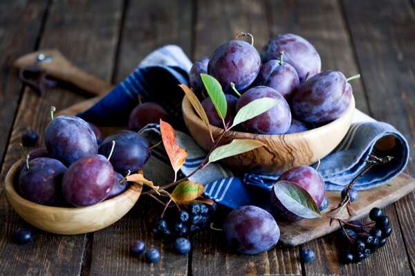 Pflaumen und schwarze Johannisbeeren auf Holztellern