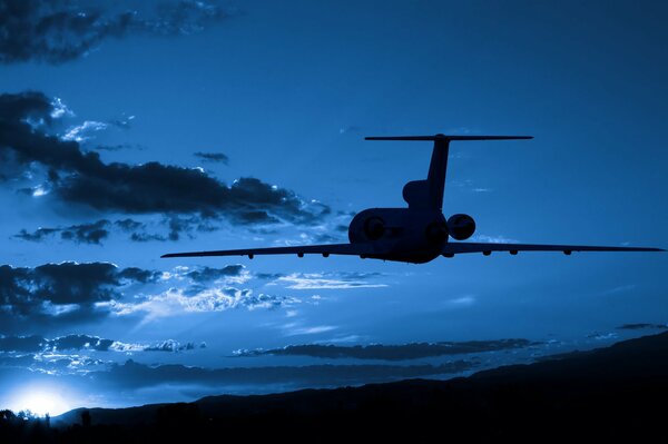 Un avión vuela por el cielo nocturno al atardecer