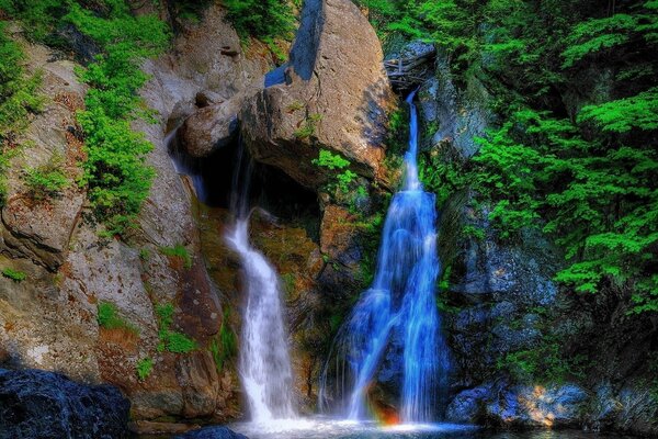 Blue and white waterfalls on the background of mountains and forests