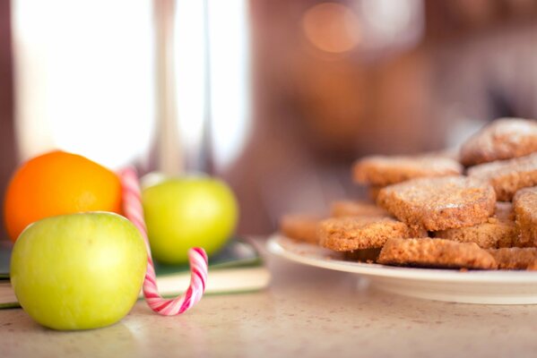 A table with apples and a plate of cookies on it