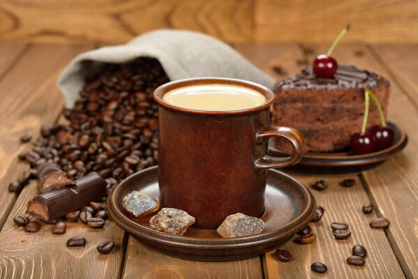 Coffee beans, coffee and chocolate cake on a wooden background