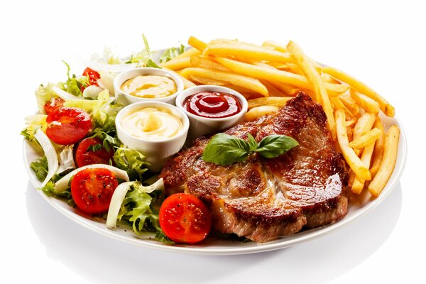 Fried meat with vegetable salad, French fries and three sauces on a white plate