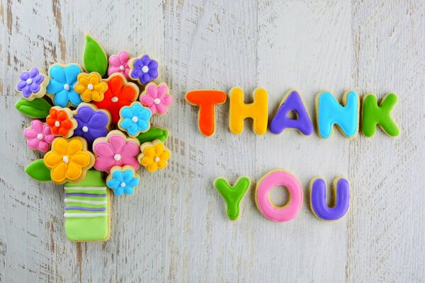 Cookies with multicolored glaze in the form of the phrase Thank You and a bouquet of flowers