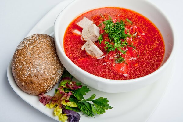 Borschtsch mit Brot in einem schönen weißen Teller mit Kräutern