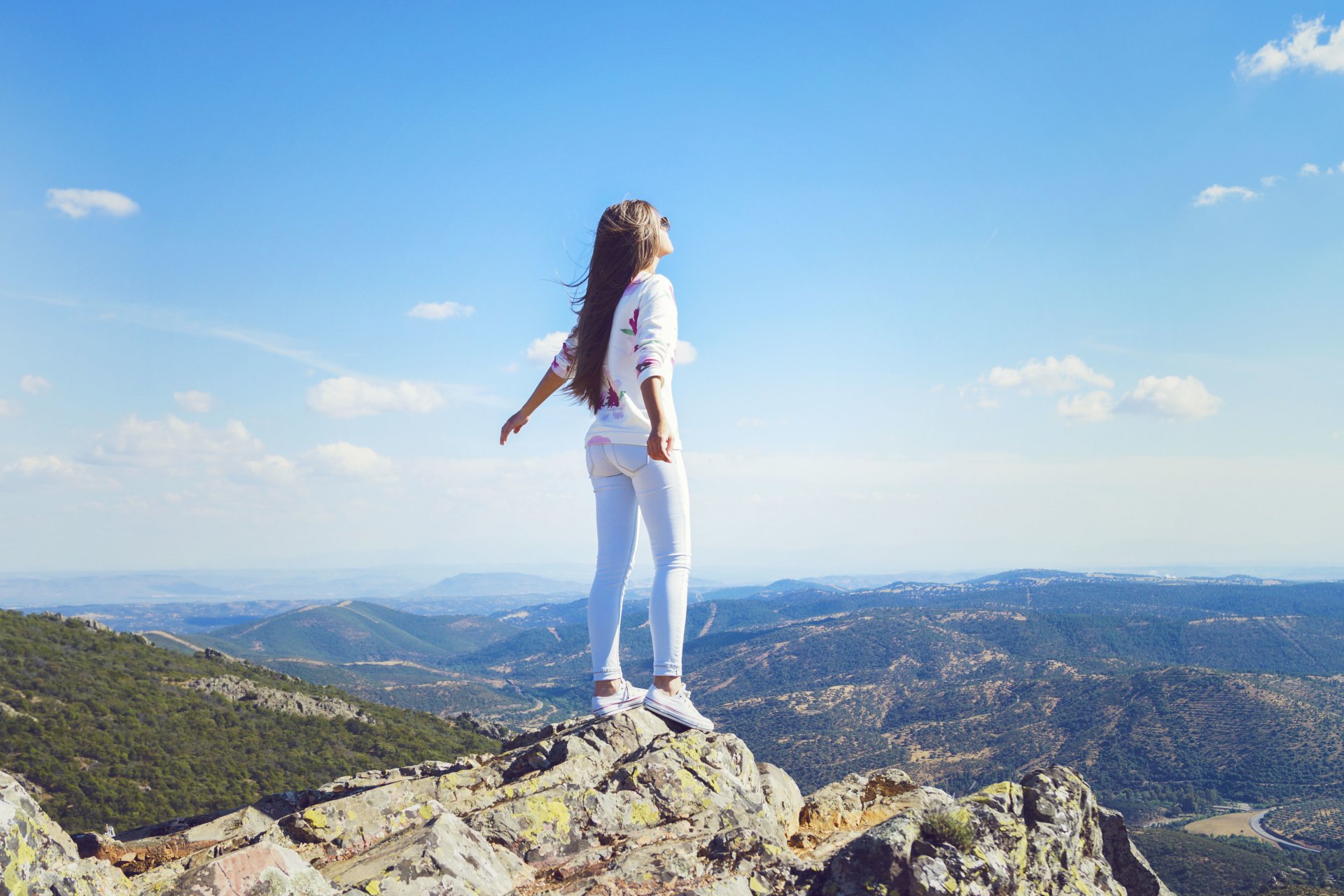 fille montagne jeans vent cheveux pose debout horizon ciel nuages