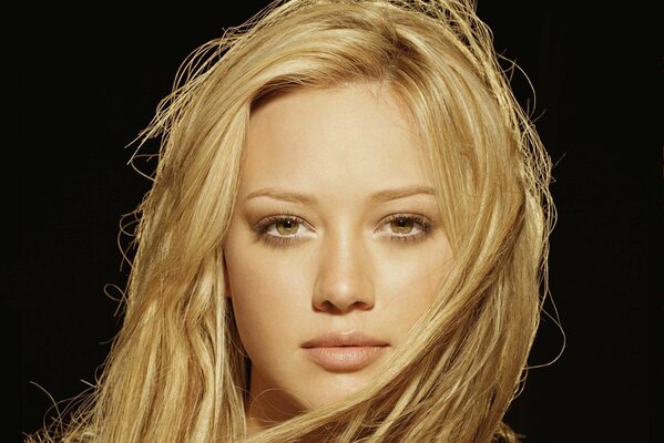 Portret Hilary Duff z bezpośrednim spojrzeniem na ciemnym tle