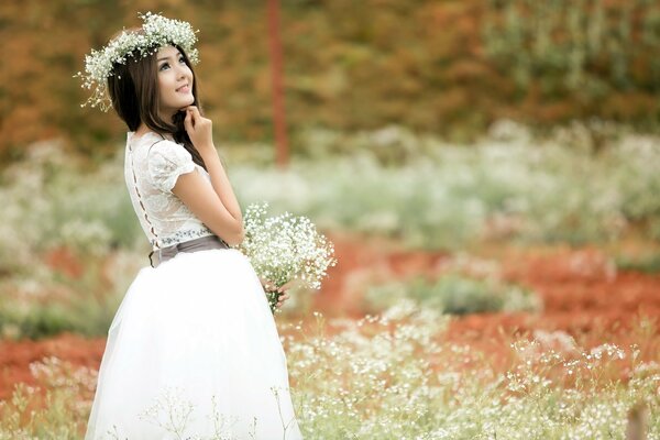 Chica asiática en vestido blanco en el campo de verano