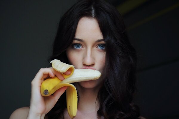 Blue-eyed beautiful brunette eating a banana